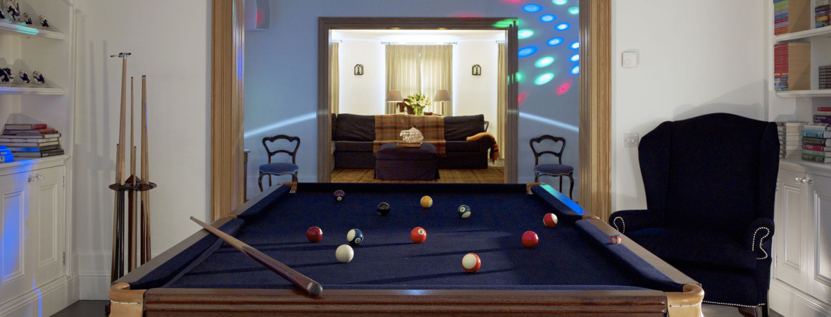 A spacious room showcasing a polished pool table, complete with cues and balls, ready for a friendly match