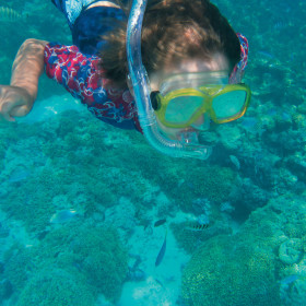 A girl snorkelling underwater with fish below her