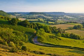 Scenic countryside view featuring a winding road surrounded by vibrant greenery and rolling hills