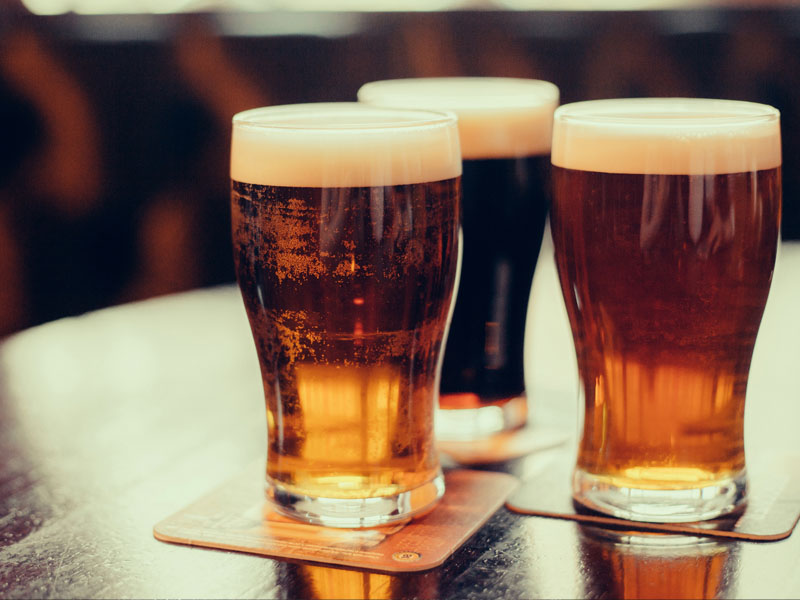 3 pints of beer on a pub table.