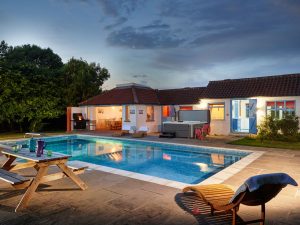 A tranquil nighttime scene showcasing a house with a pool and a beautifully lit patio area