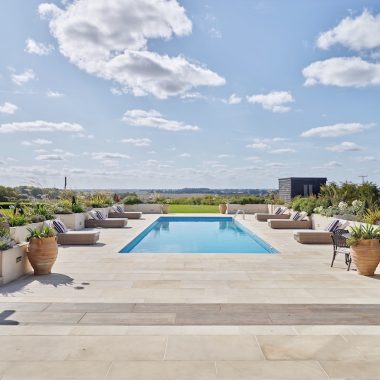 A serene pool and patio with lounge chairs, offering a beautiful view of the surrounding countryside