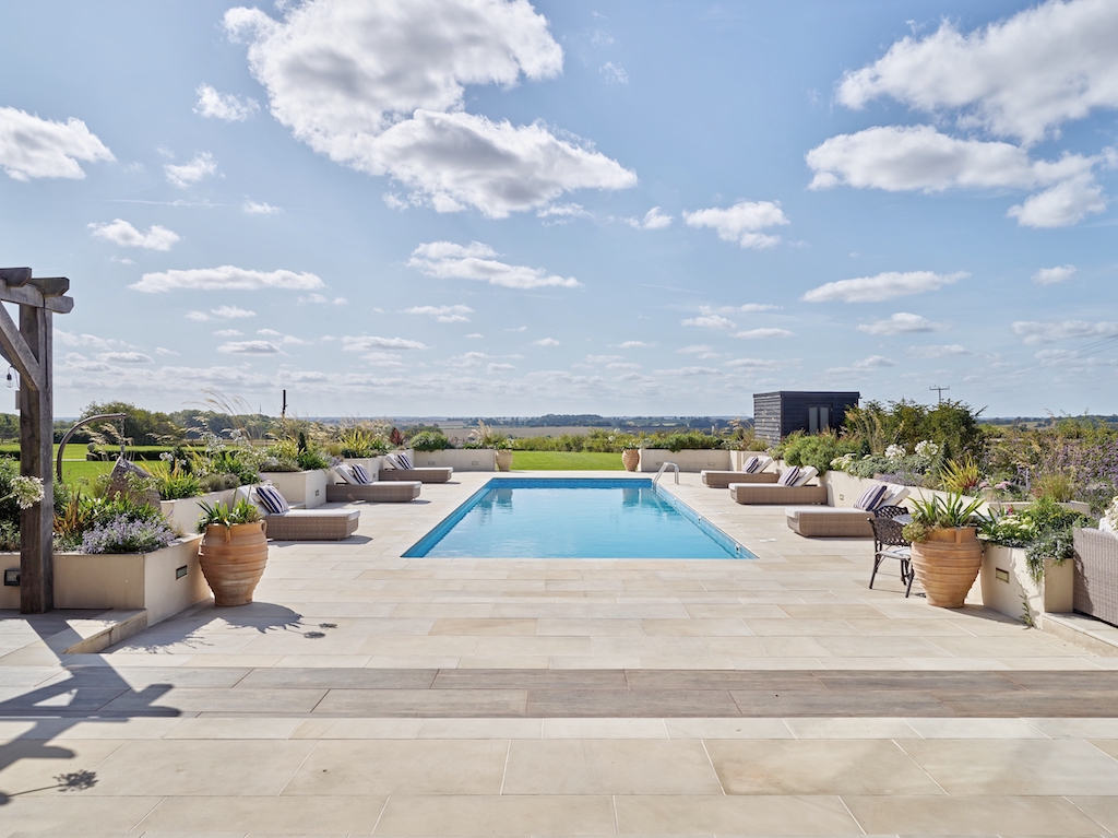 A serene pool and patio with lounge chairs, offering a beautiful view of the surrounding countryside