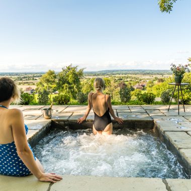 Two friends relax in a hot tub, enjoying a scenic view of nature around them