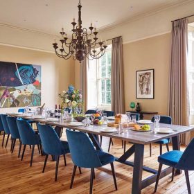 A spacious dining room featuring a large table surrounded by several chairs, creating an inviting atmosphere for gatherings