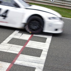 Race car crossing the finish line on a circuit.