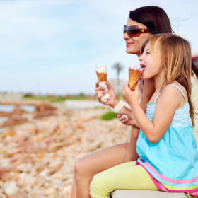 Mum and daughter enjoy fun ice cream at the beach.