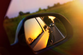 Rear view mirror of a Car looking back.