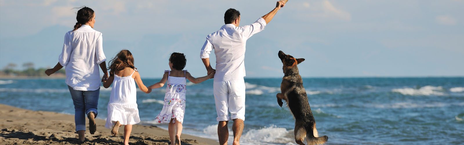Family on a beach walking their dog.