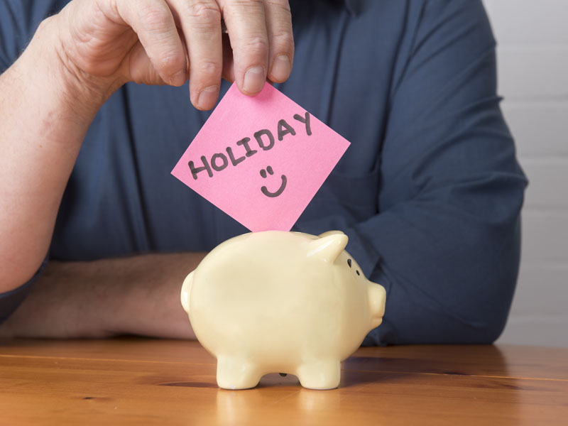 Man putting the word holiday into a money box.