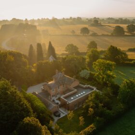 Aerial view of a charming holiday house surrounded by lush greenery and open fields