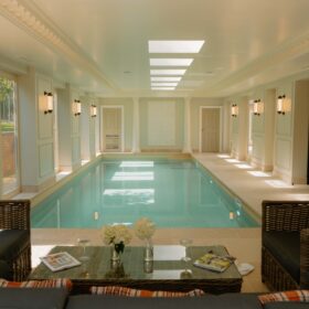 An inviting indoor pool surrounded by plush couches and chairs, perfect for unwinding in a home setting