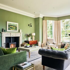 A stylish living room in a large holiday cottage adorned with green walls and a charming open fire, perfect for relaxation and taking time away from everyday life