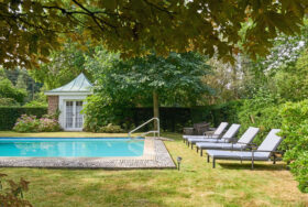 A swimming pool with three sun loungers to the side