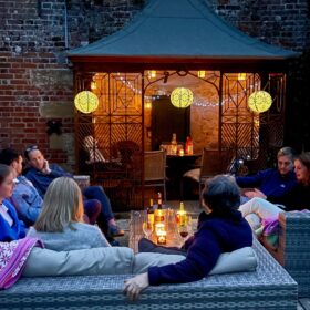 A group of family and friends gathered around a patio table in the twilight